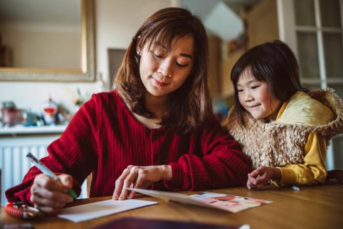 أم شابة جميلة تكتب بطاقة تهنئة للعائلة مع ابنتها الجميلة في المنزل