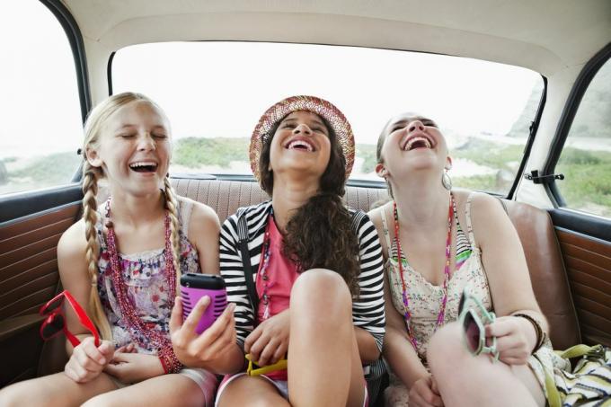 ثلاث فتيات يضحكن في المقعد الخلفي للسيارة