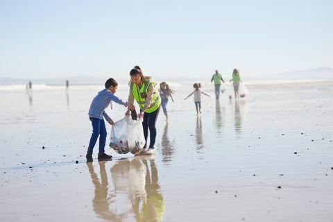 متطوعو الأم والابن ينظفان القمامة على الشاطئ الرملي الرطب