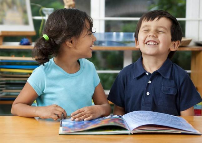 طفلان يضحكان يستمتعان بكتاب في المدرسة