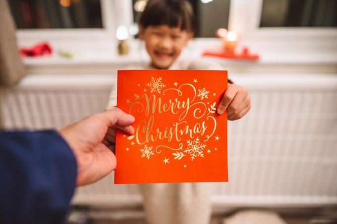 منظور شخصي لأب يتلقى بطاقة عيد الميلاد مقدمة من ابنتها الجميلة المبهجة في عيد الميلاد في المنزل مفهوم الاحتفال بعيد الميلاد مع العائلة في المنزل