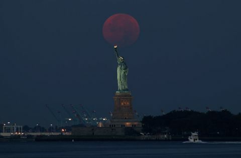 اكتمال القمر يجلس خلف تمثال الحرية في مدينة نيويورك