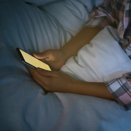 امرأة تستخدم الهاتف الذكي في السرير ليلاً، ومشكلة النوموفوبيا المقربة واضطراب النوم