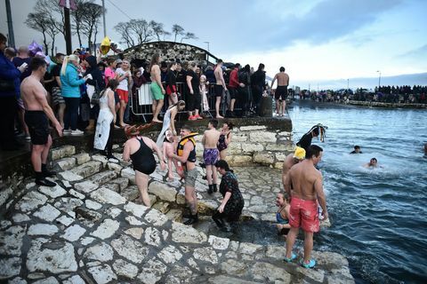 كارنلاو ، أيرلندا الشمالية ، 01 يناير ، حشد كبير من المتفرجين يشاهدون السباحين وهم يشاركون في السباق السنوي الجديد يوم لسنوات السباحة في مرفأ كارنلاو في 1 يناير 2018 في كارنلاو ، أيرلندا الشمالية ، تصوير تشارلز ماكويلانجيتي الصور